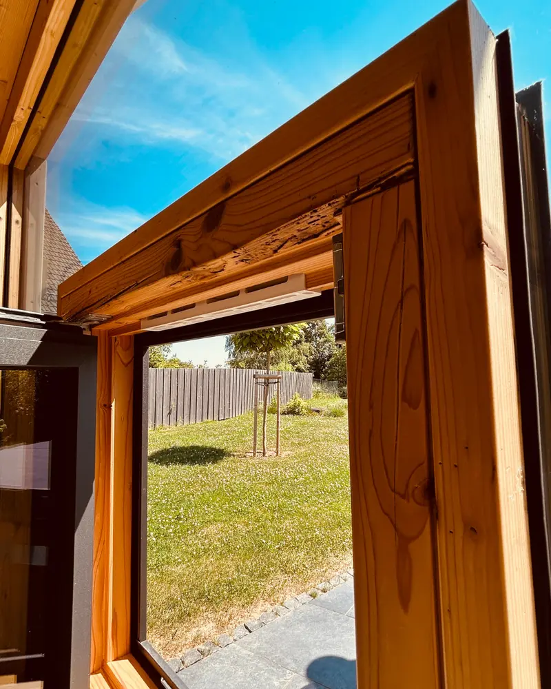 Nahaufnahme eines Fensterrahmens aus recyceltem Holz mit natürlichen Gebrauchsspuren und gewachsener Struktur