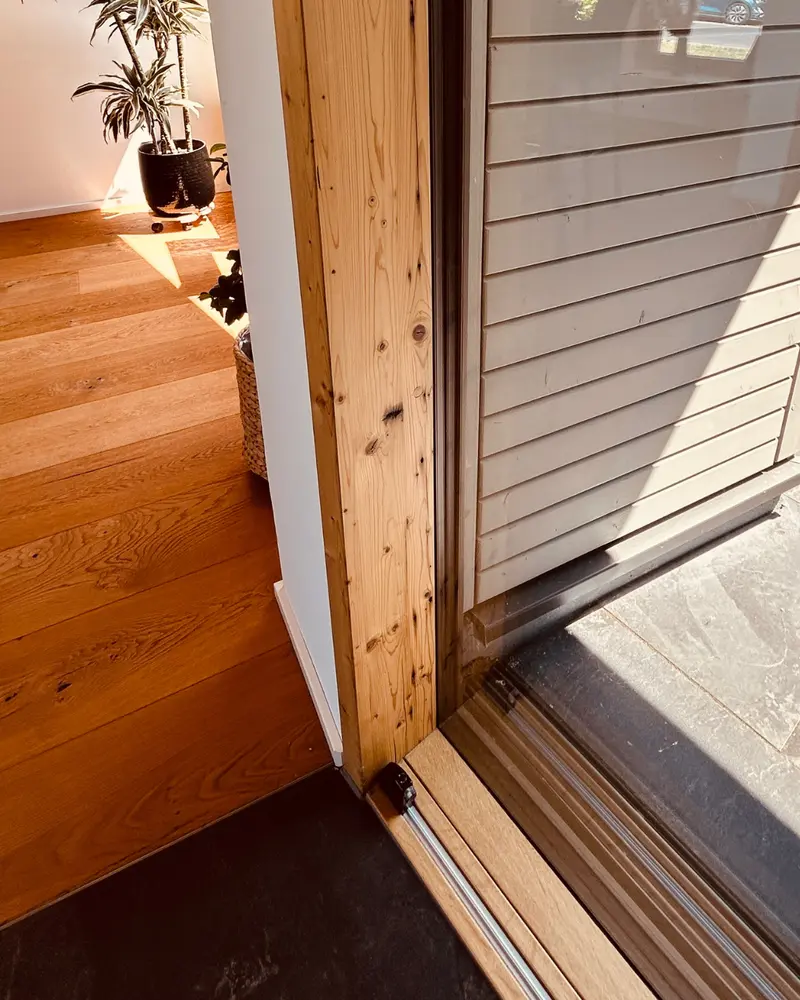 Detailansicht eines Holzrahmens im Übergang zum Boden mit sichtbarer Verarbeitung und natürlicher Materialstruktur