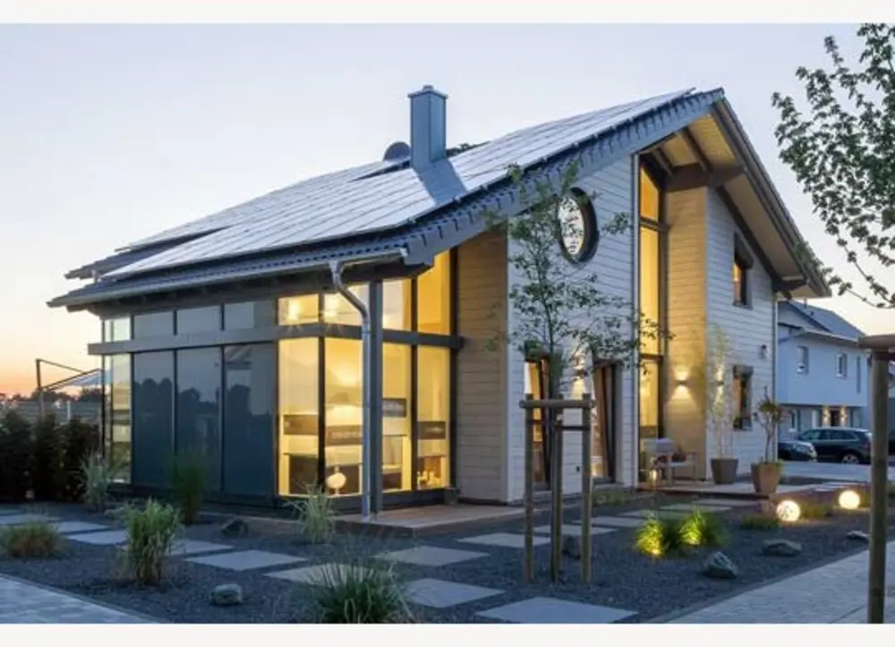 Moderne Stadtvilla aus Holz mit großer Photovoltaikanlage und bodentiefen Fenstern bei Dämmerung.