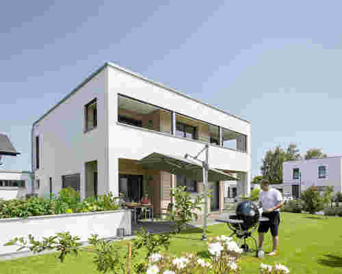 Blick auf weißes Holzhaus im Bauhausstil mit Garten