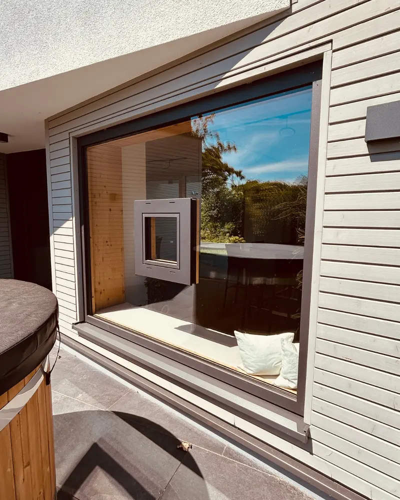Außenseite eines großen Fensters mit integriertem kleinen Fensterrahmen als Designelement in der Glasfläche