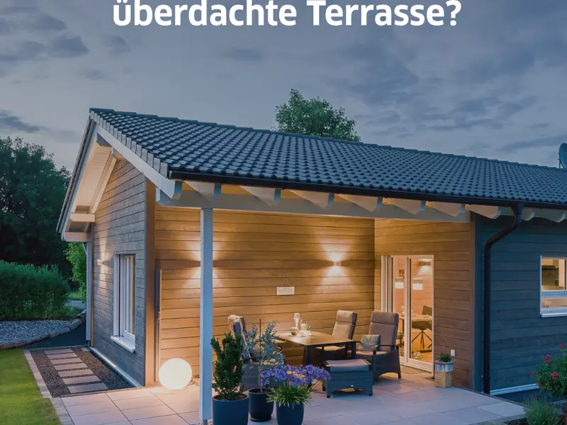 Modernes Holzhaus mit großzügig überdachter Terrasse am Abend. Die überdachte Außenfläche verbindet Wohnraum und Garten und zeigt eine mögliche Lösung für Veranda, Porch oder Terrassenüberdachung bei einem individuell geplanten Holzhaus von Stommel Haus.