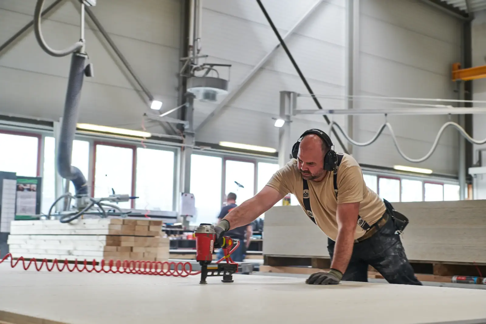 Mitarbeiter von Stommel Haus verarbeitet ein Wandelement mit einem Drucklufttacker in der Fertigung.